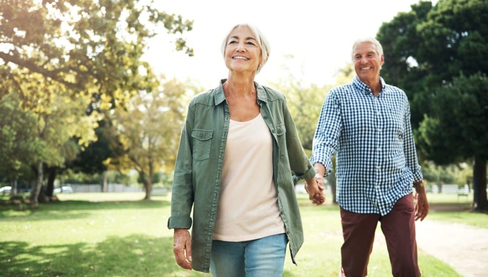 An older couple walking in the woods.