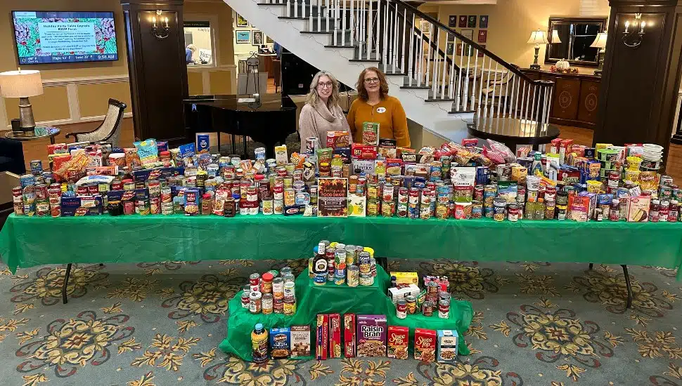 Freedom Village food drive organizers stand behind a table covered with collected food.