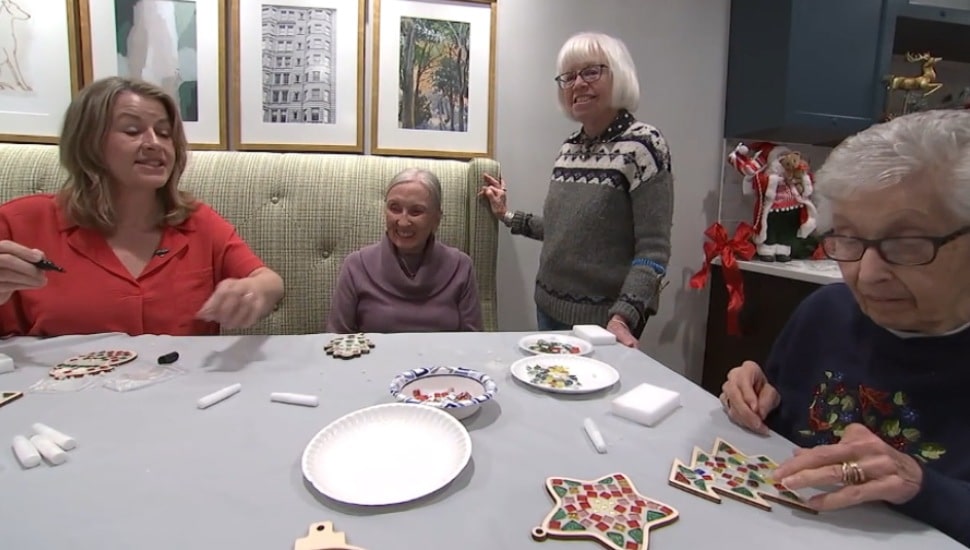 Helen Smith, (seated, in red) works on art projects with residents of Rose Tree Place along with Marsha McGlinchey (standing).