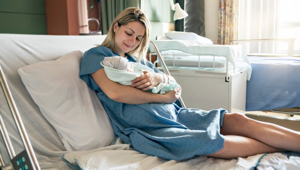 A woman rests in a hospital bed with her new baby.