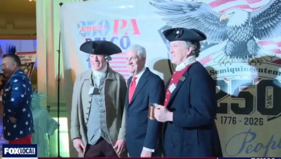 Two men in Colonial garb join a third man for a photo op.