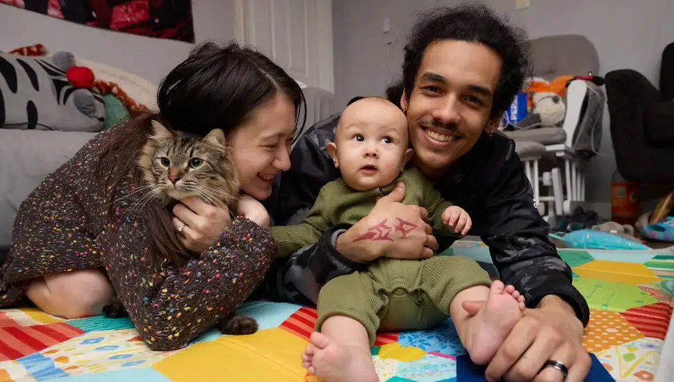 A man and woman happily spend time with their baby.