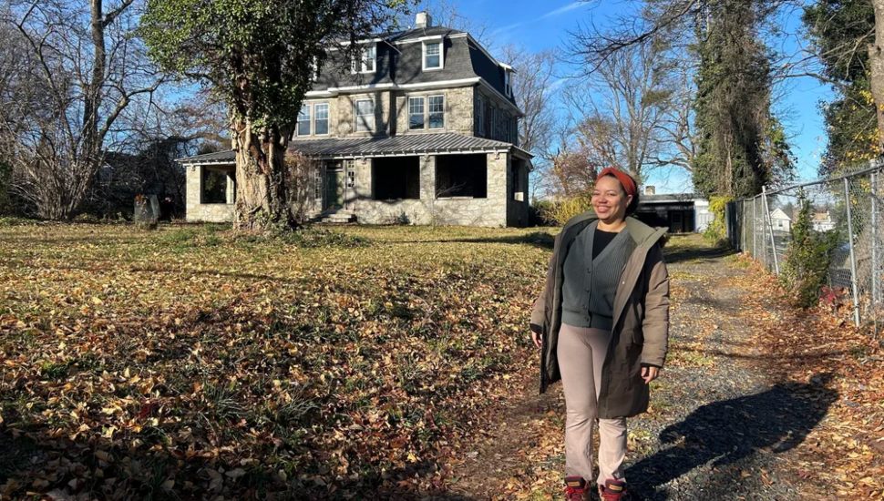 A woman stands on the grounds of a 100-year-old historic house in Germantown, site of hte Philadelphia Midwife Collective.