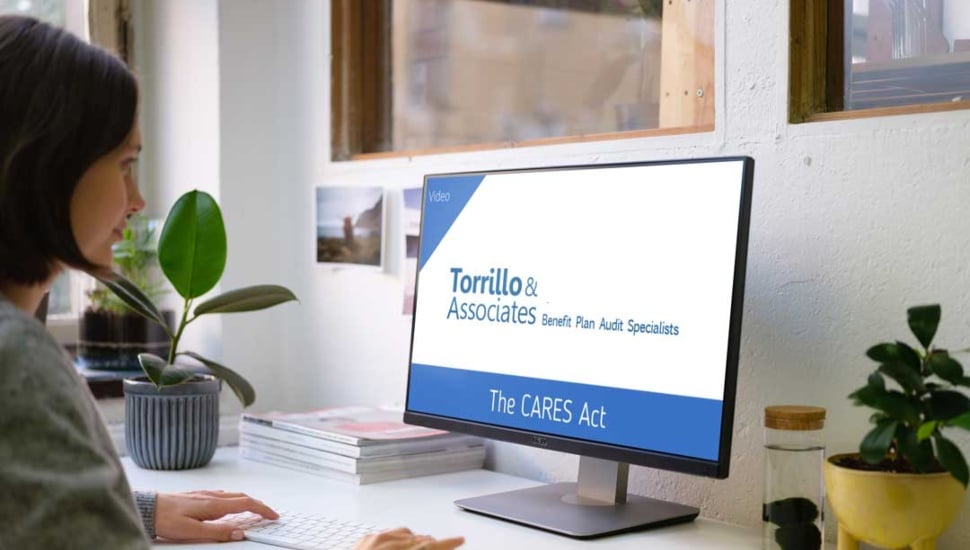 A woman looks at a desktop computer screen with the words "Torrillo & Associates on the screen.
