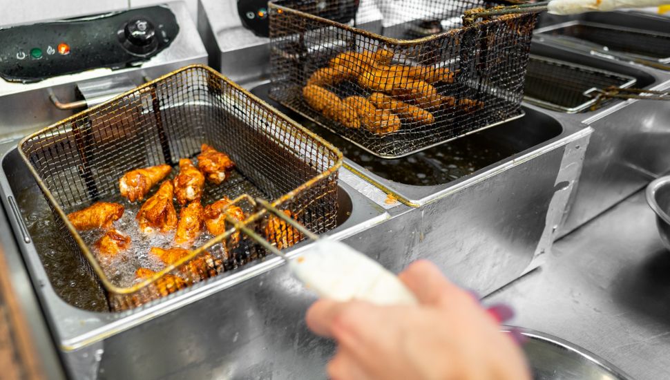 A chef prepares wings in a deep fryer.
