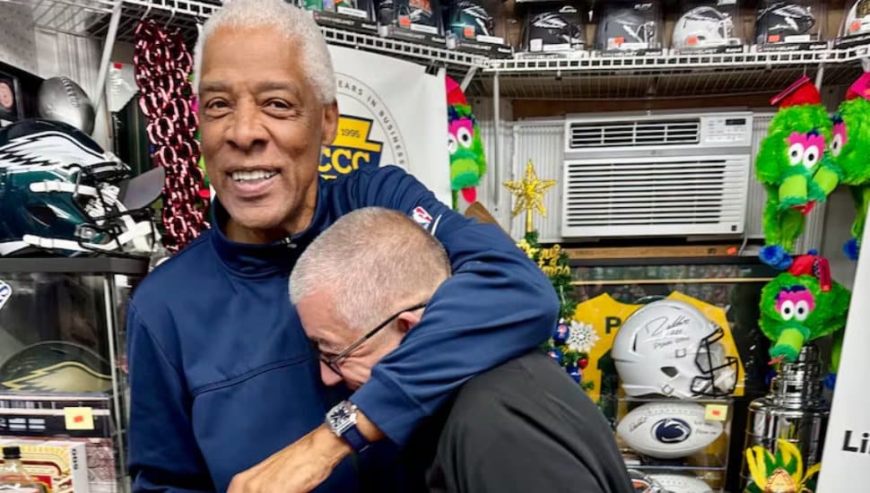 Julius Erving shares a hug with Carl Henderson (right).