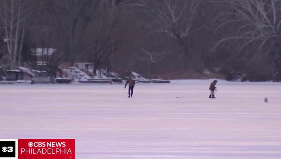 Two people are spotted walking on the frozen Schuylkill River.