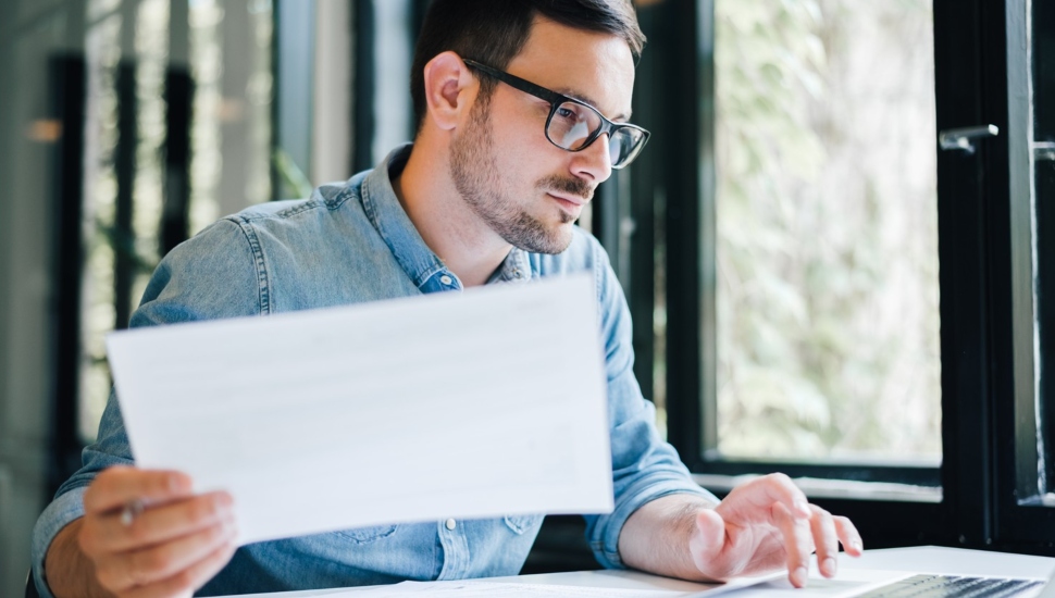 Young male bookkeeper in glasses works at laptop computer.