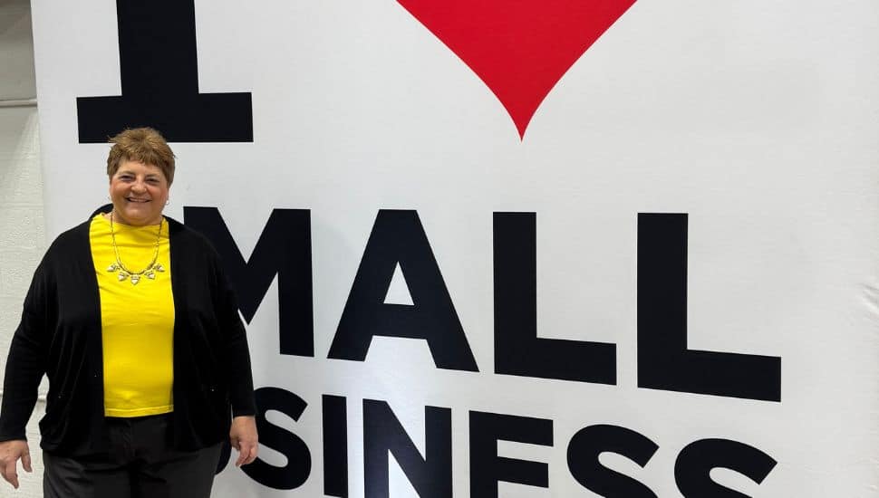 Lynne Williams in front of the I live Small Business sign.