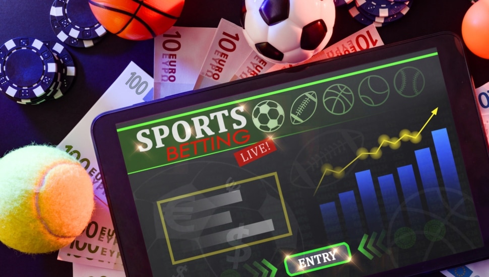 Online sports betting with tablet with application in the center of a black table.