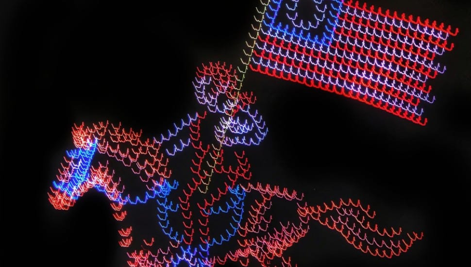A drone show on the Fourth of July shows a man on a horse carrying the American Flag.