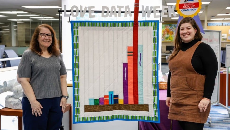 Laura Guertin and Annie Jansen standing in front of Love Data Week Quilt.