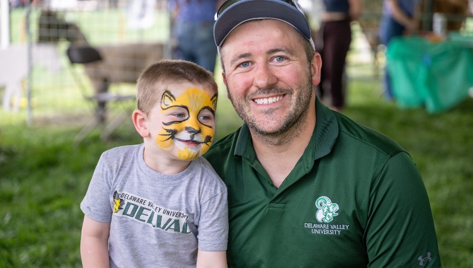 Father and son with face painted at agricultural fair.