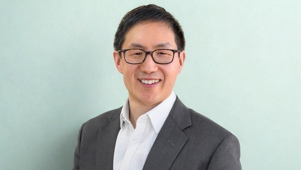 Headshot of middle-aged male doctor in glasses and open-collared shirt.