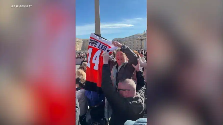 A custom-made Flyers jersey with Pope Leo's name is held up just before presenting it to the Holy Father.