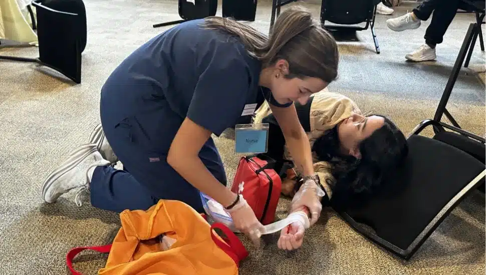 A student first responder treats an injured person during a simulated disaster event.