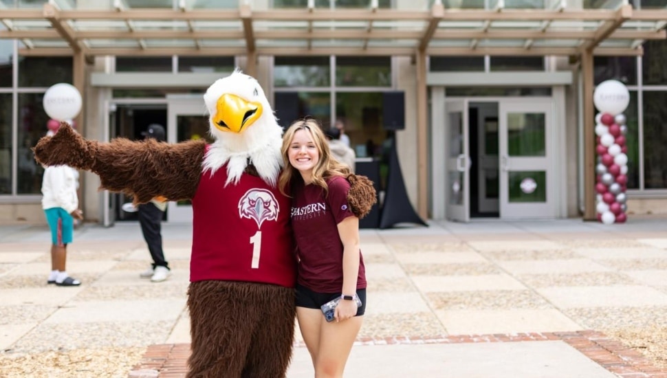 Eagle mascot hugs college student.