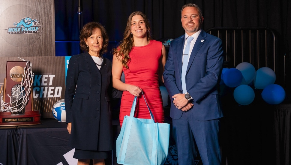 College valedictorian poses for picture with school president and athletic director.