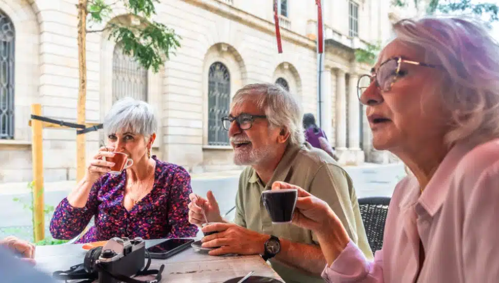 A group of seniors drink coffee and talk together.