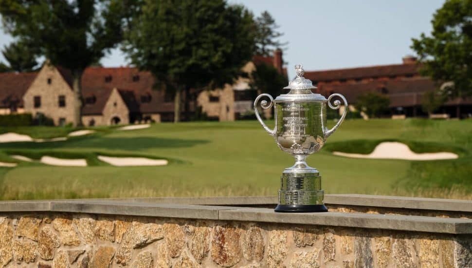 Wanamaker Trophy on stone wall with Aronimink Golf Club buildings in the background.