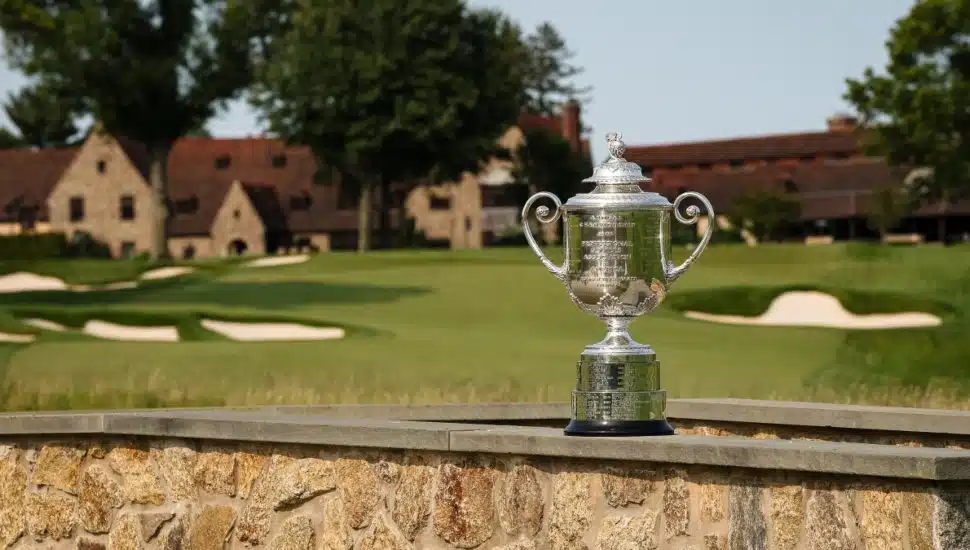 Wanamaker Trophy on stone wall with Aronimink Golf Club buildings in the background.