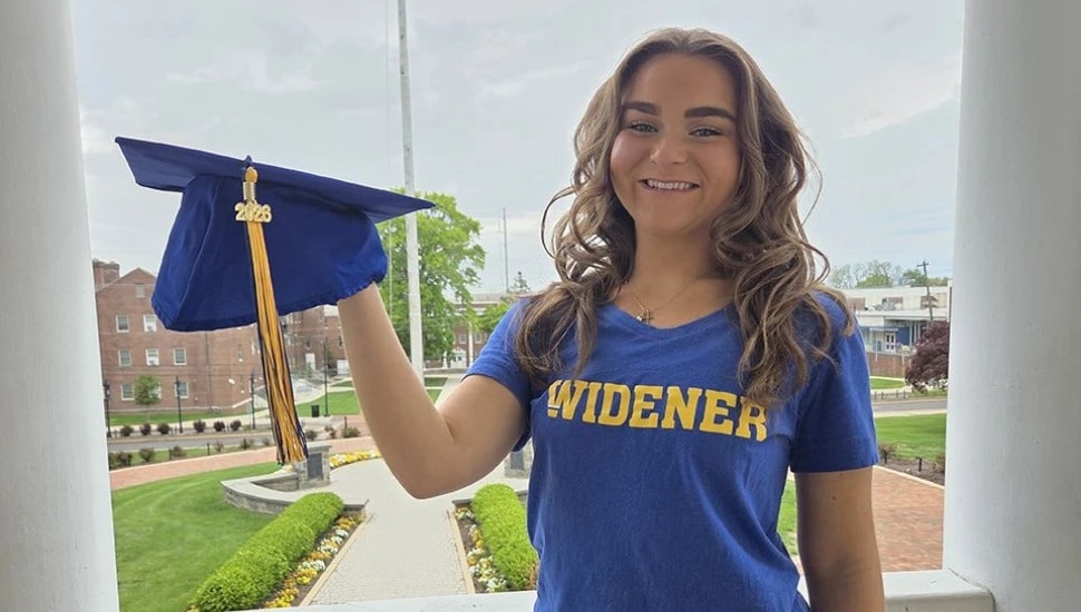 Amanda Rappa, with graduation cap in hand, poses on the Widener University campus.
