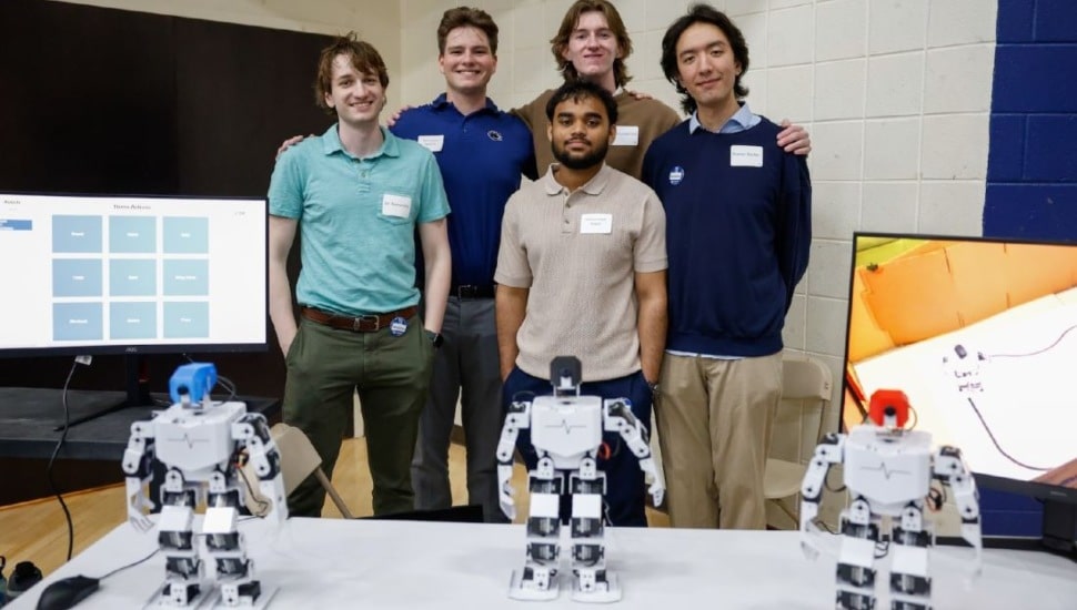 Five Brandywine students stand behind three robots.