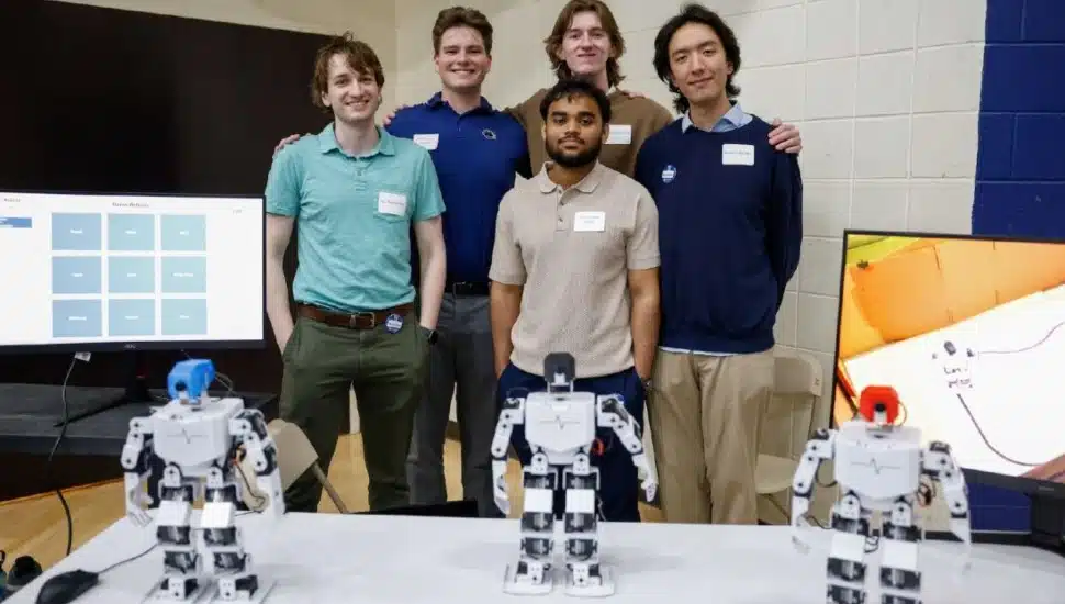 Five Brandywine students stand behind three robots.