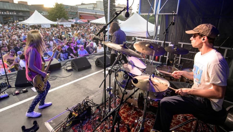 Band playing at the Wayne Music Festival to a crowd of onlookers.