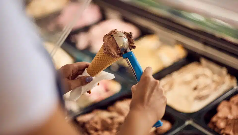 Close-up of a chocolate ice cream in a cone, putting with a scooper.