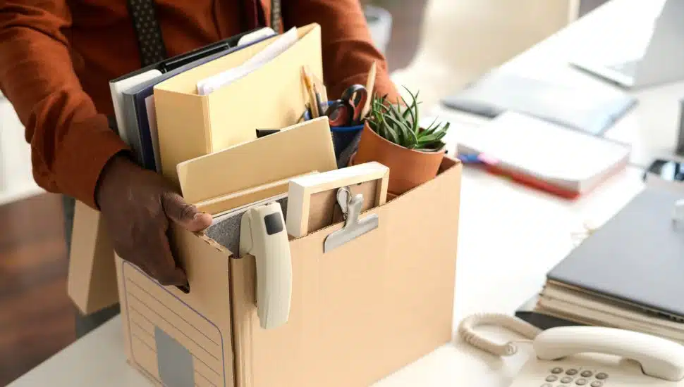 Man carrying office supplies in a cardboard box.