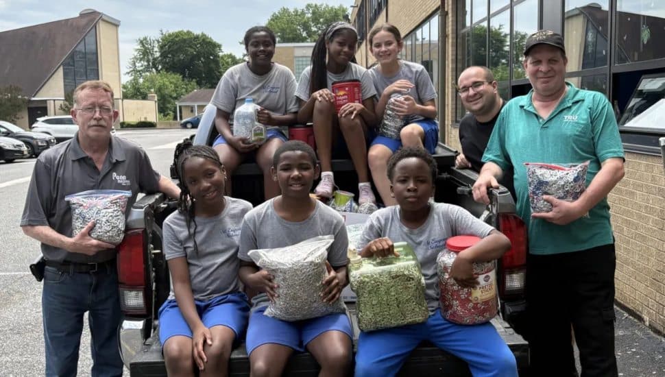 Students from St. Eugene Catholic High School with Mark Loomis and Stephen Mellon sitting on a truck with bags of soda tabs.