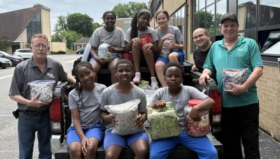 Students from St. Eugene Catholic High School with Mark Loomis and Stephen Mellon sitting on a truck with bags of soda tabs.