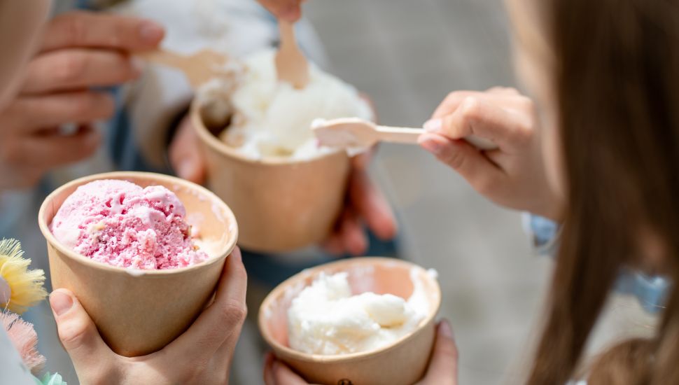 Kids and adult eating ice cream with spoons out of cups.
